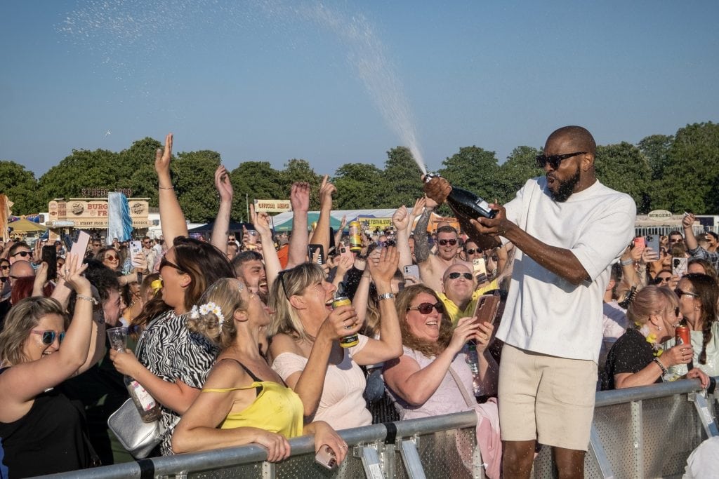 Music popstar in the crowd spraying bottle of champagne into the crowd