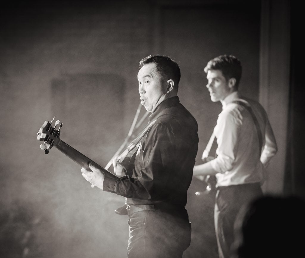 A black and white photo of two men playing guitars.