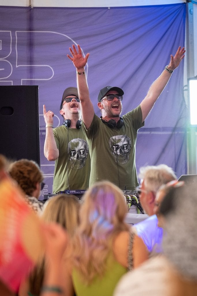Two djs at a festival with their hands up.