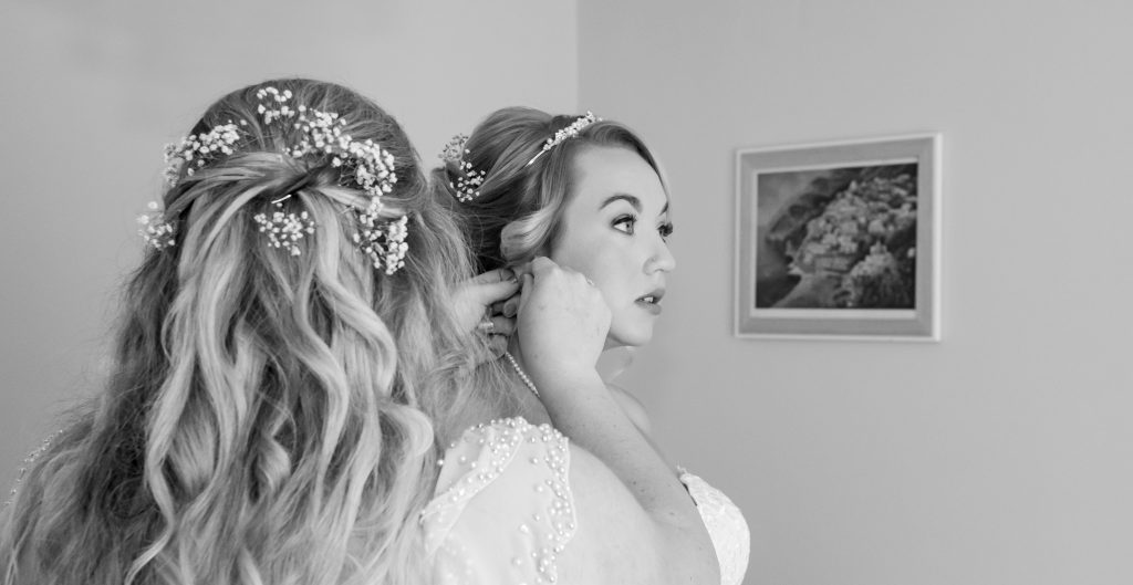 A bride is getting her hair done in front of a mirror.