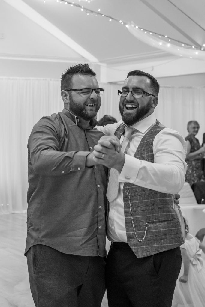 Two men dancing at a wedding reception.