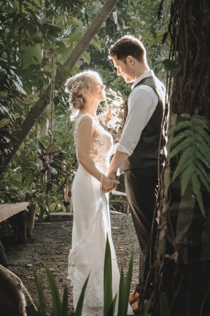 A bride and groom standing together in the jungle.