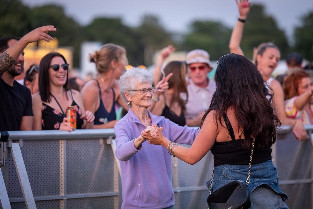 A woman is dancing with an older woman at a music festival.