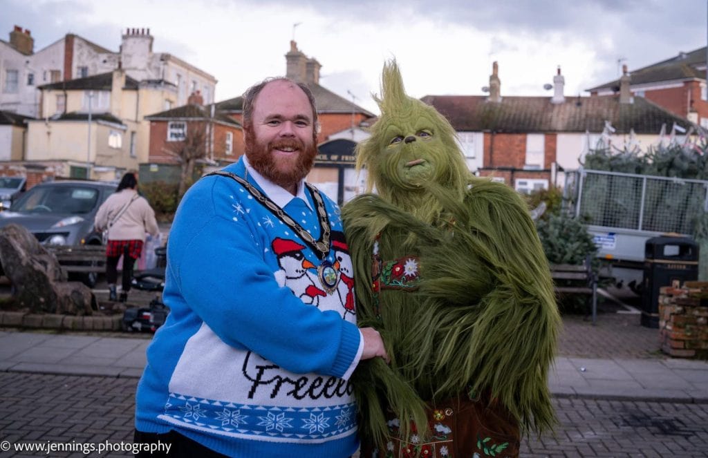 A man dressed as a grinch is standing next to a man dressed as a grinch.