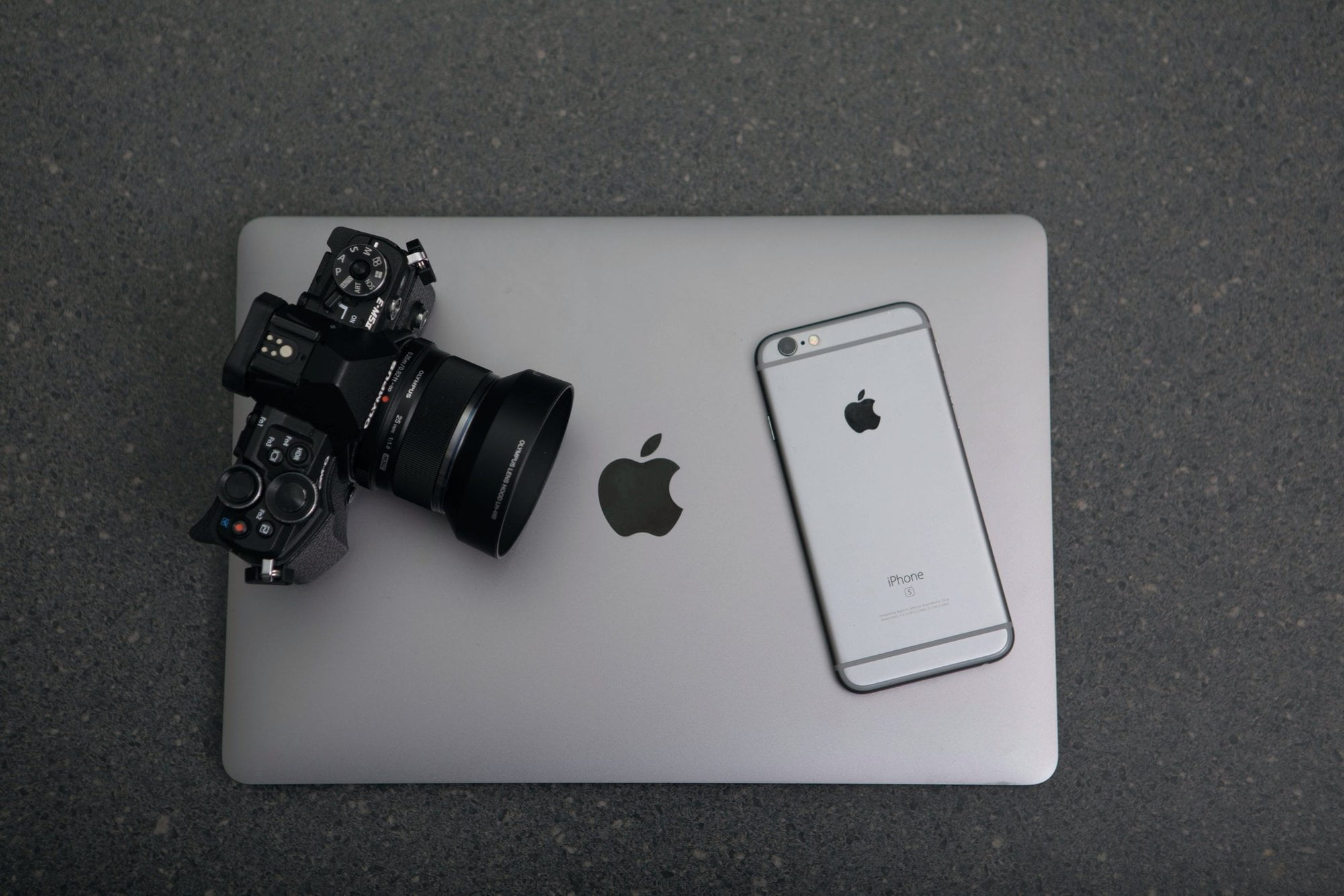 An iphone and a camera on top of a laptop.