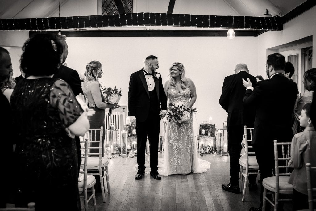 A couple stands at the altar during a wedding ceremony, surrounded by guests in an elegantly decorated venue.