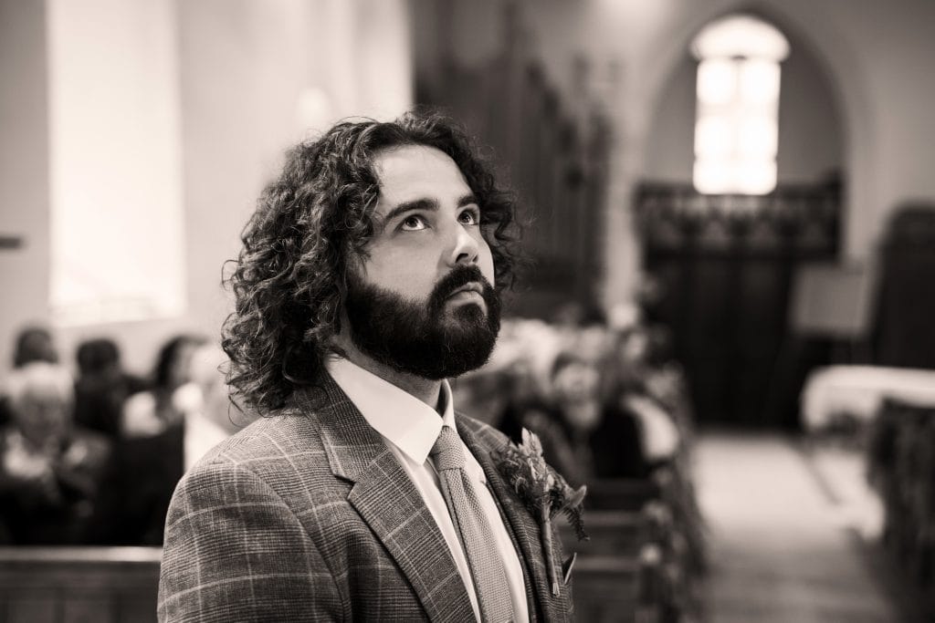 A man looking up in All Saints Church, admiring the intricate architecture above.